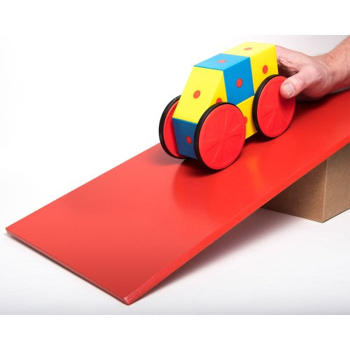 Hand rolling wheeled magnetic cube blocks on a red mat, yellow and blue blocks visible
