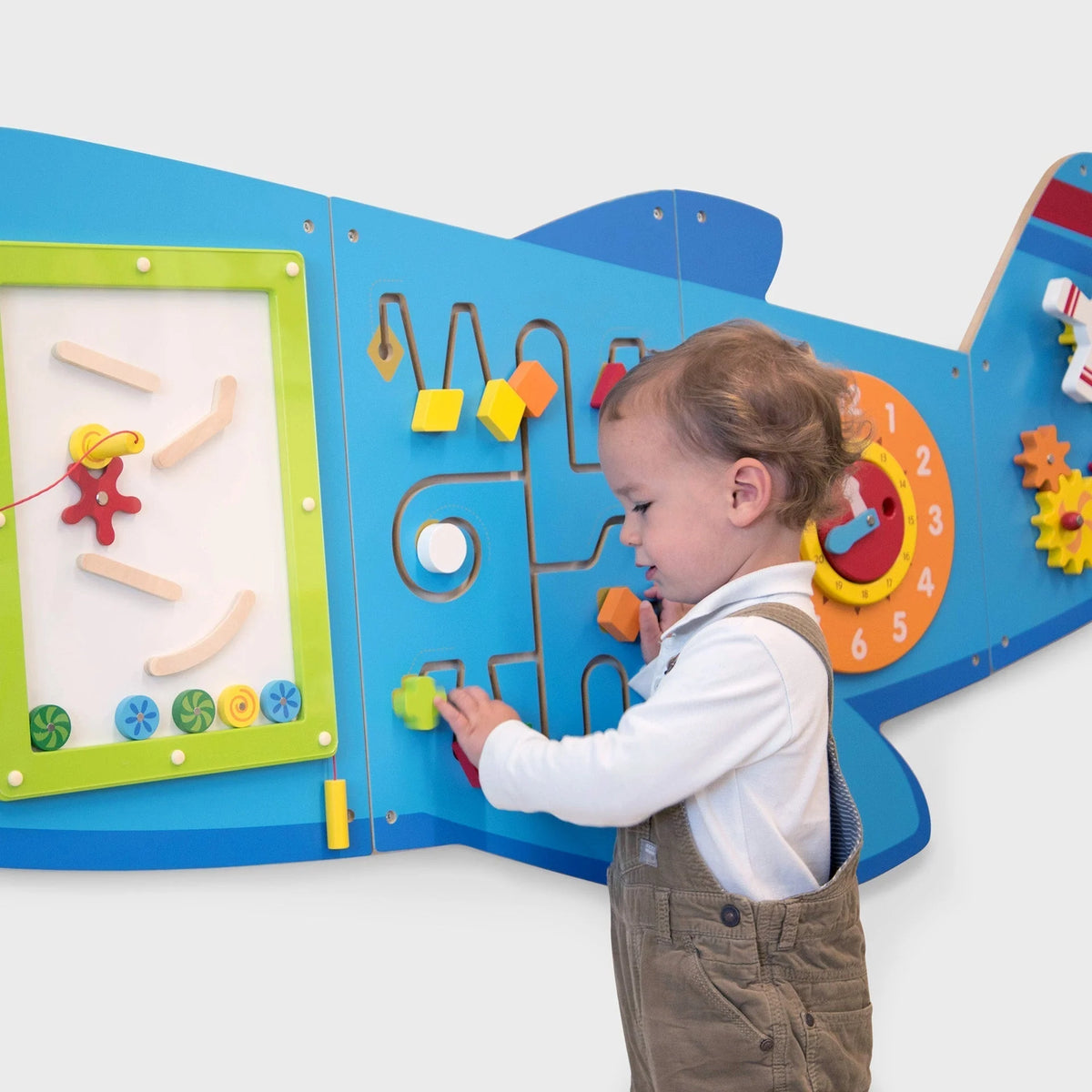 Blue airplane wall activity board with open panel, gears, and clock; child touches pegs