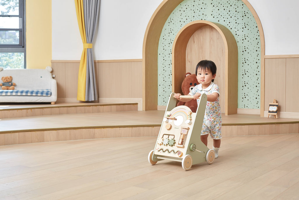 Activity baby walker with rainbow arch; toddler standing and holding the handle