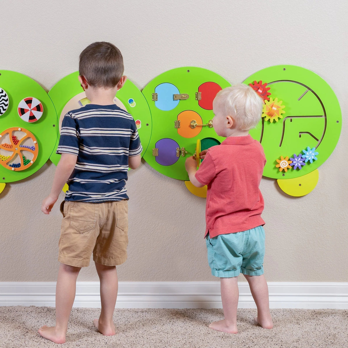Caterpillar activity wall panels with gears, spinners, and flowers on a green display