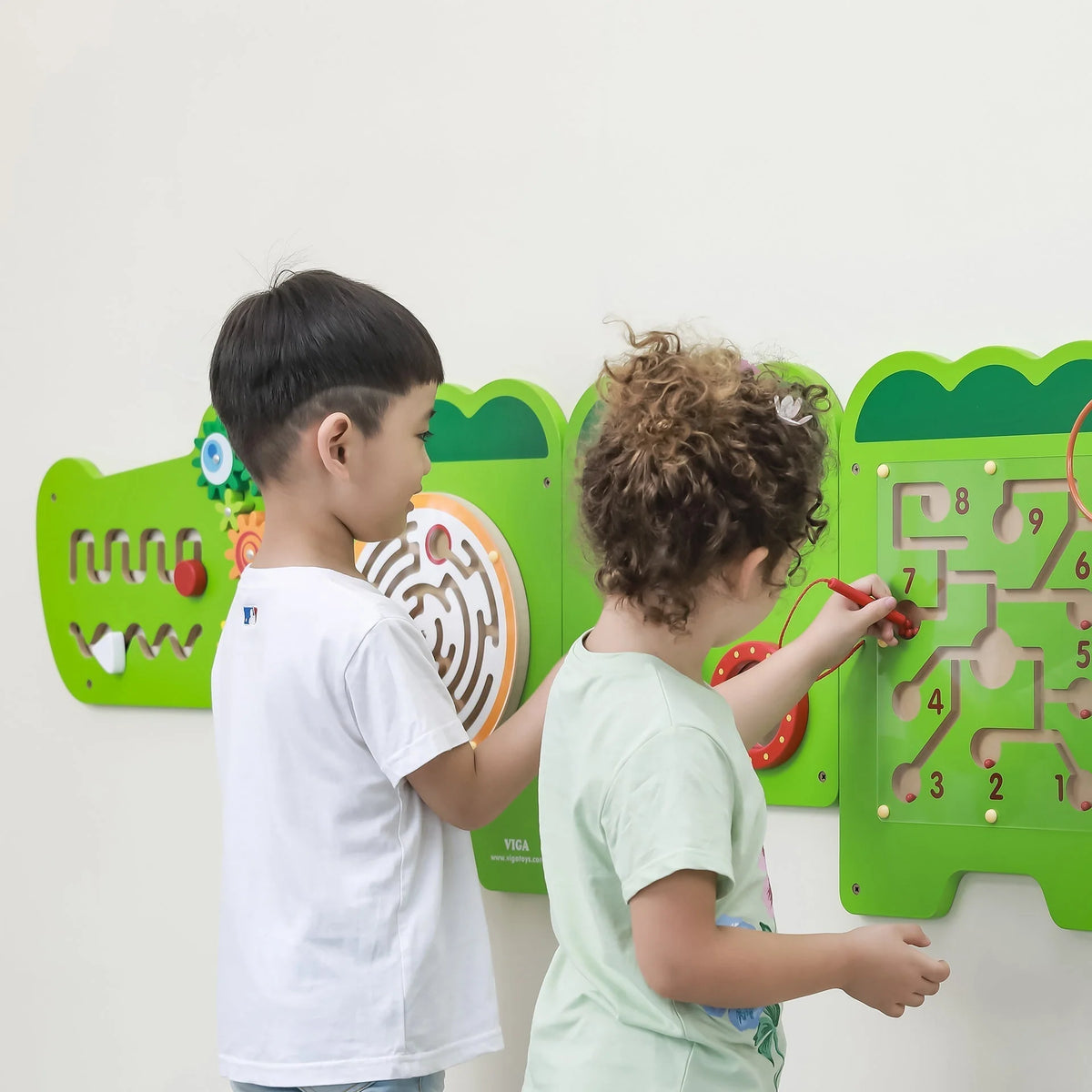 Green crocodile activity wall panels with number track, spinning parts, and maze; kids play