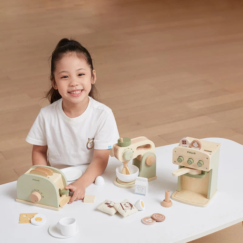 Toddler kitchen playset on table with pretend stove and food accessories; child plays beside it