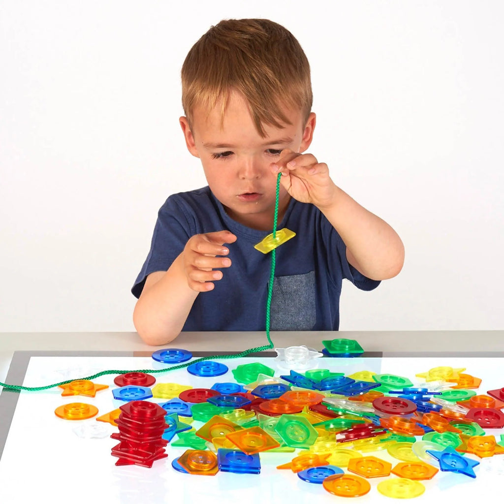 Translucent stackable buttons scattered on table with green string