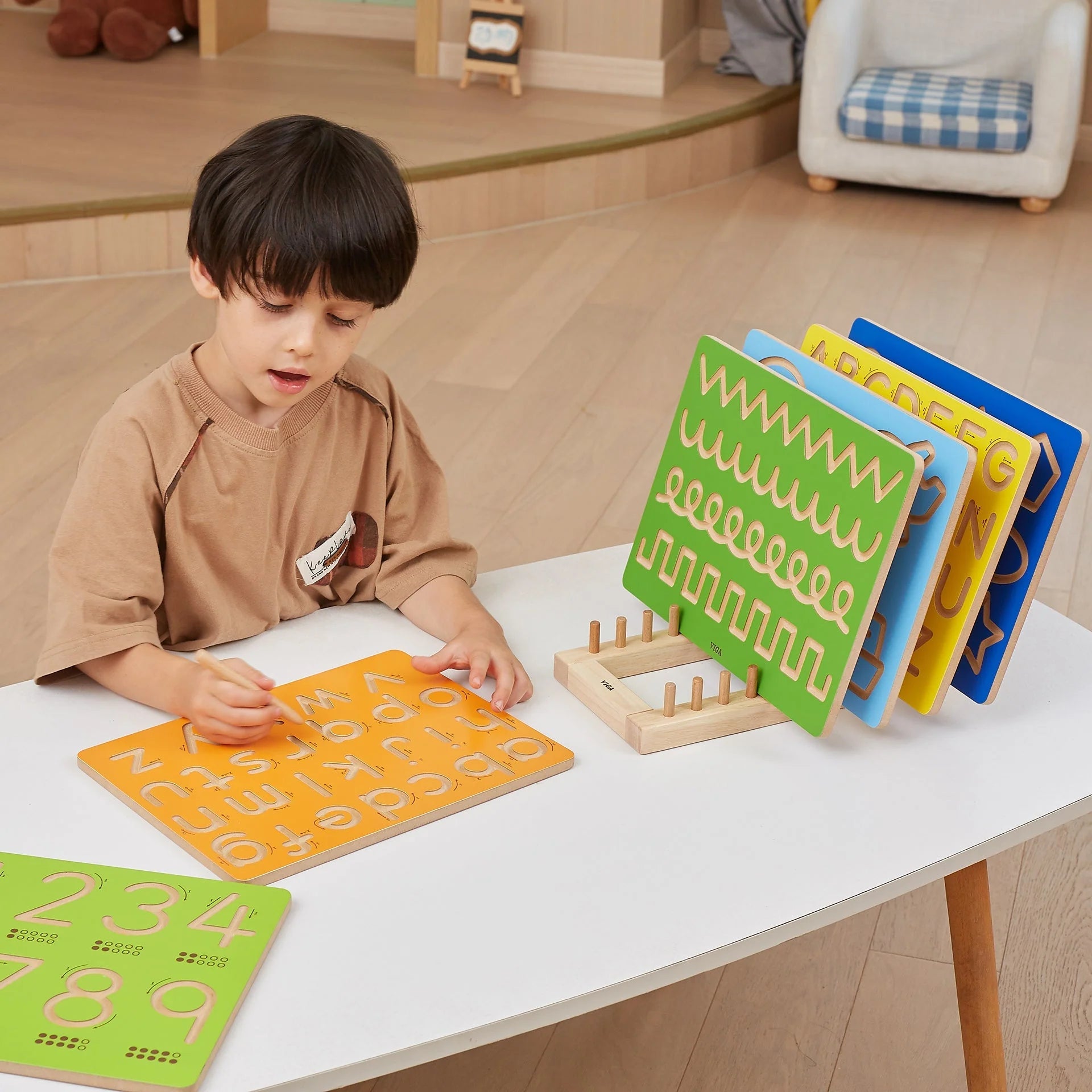 Colorful uppercase letter tracing boards on a table, child using one
