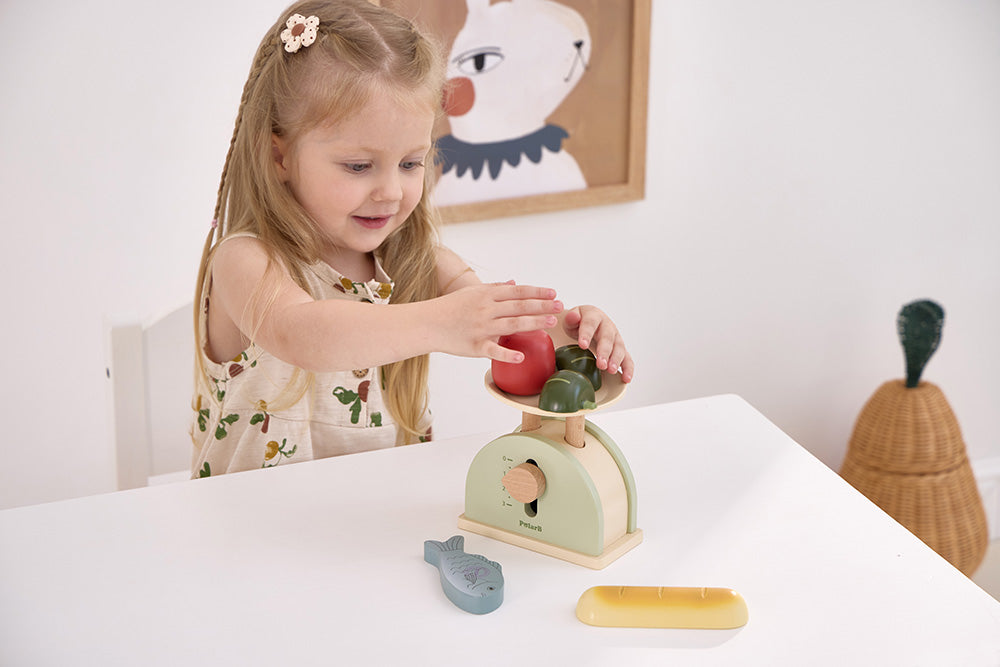 Toy weighing scale in mint green on table, child playing with wooden dial