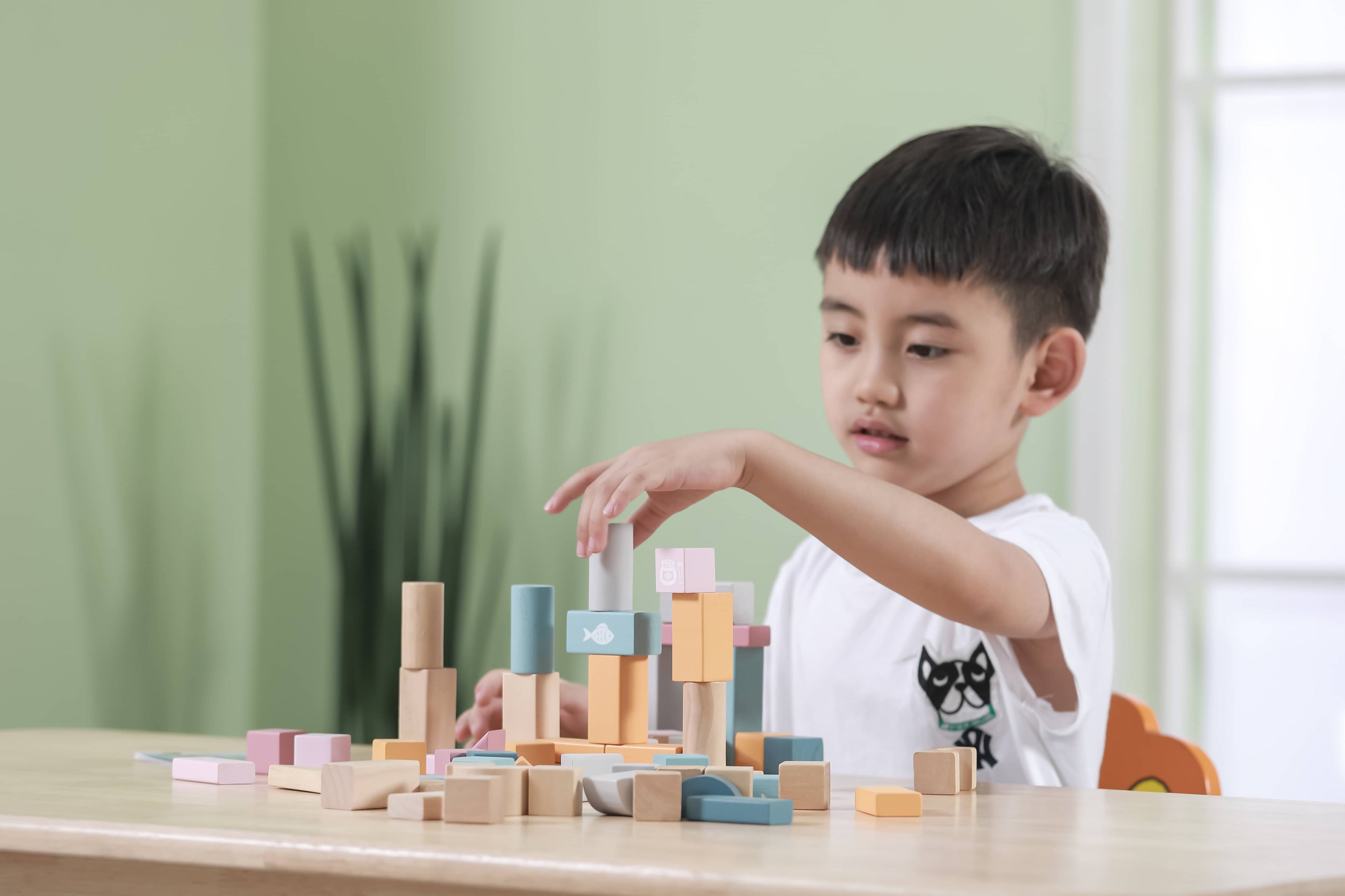 Wooden blocks on a table, with a child playing nearby