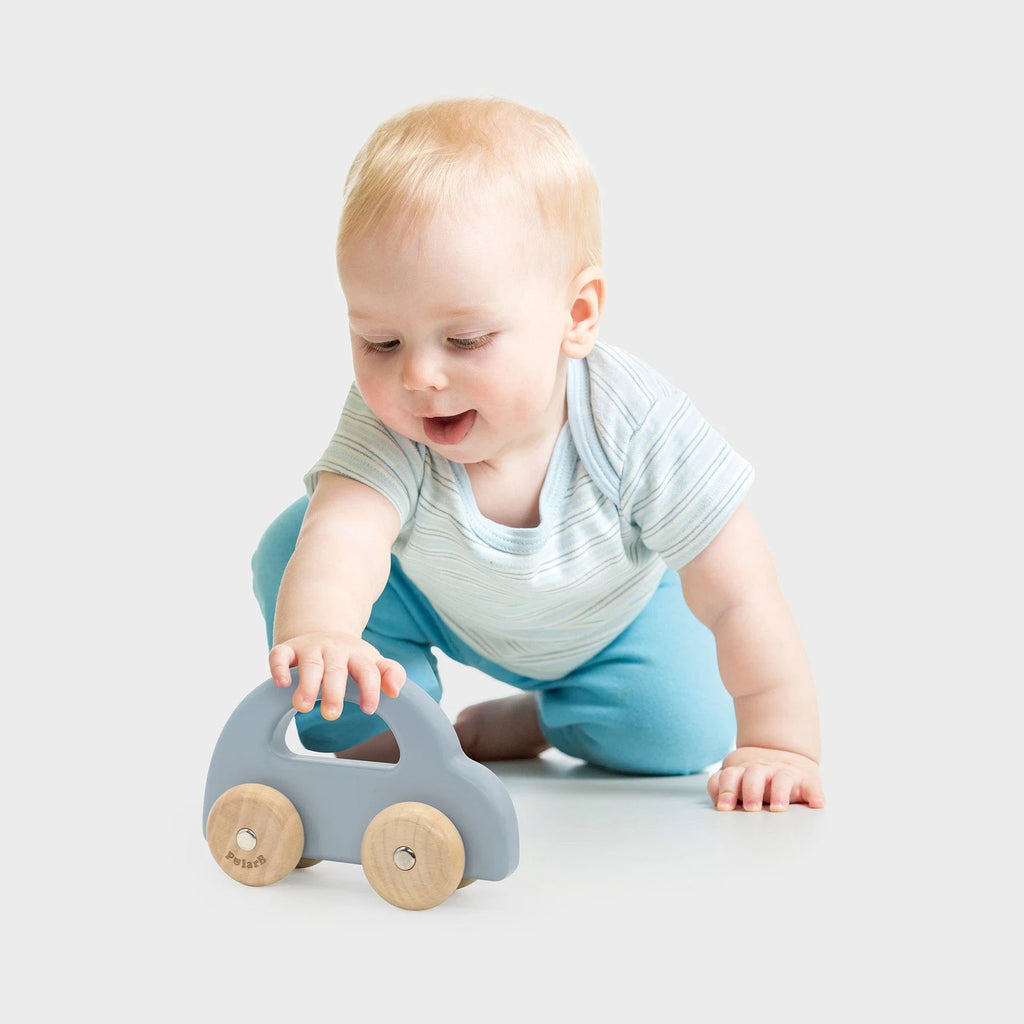 Child playing with a blue wooden toy car with two wooden wheels and handle