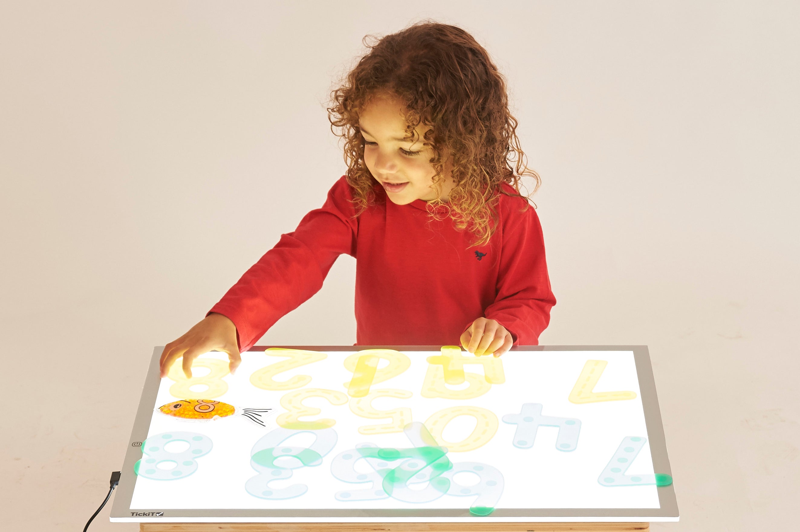 Kids using a glowing color light panel with translucent shapes on the surface