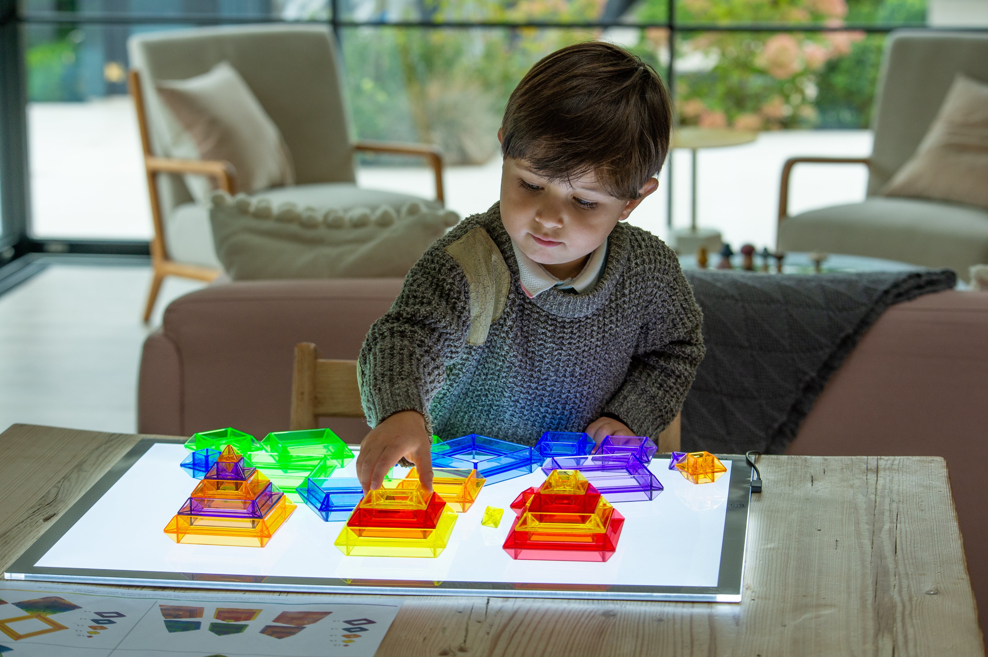 Child arranging colorful blocks on a glowing LED light panel