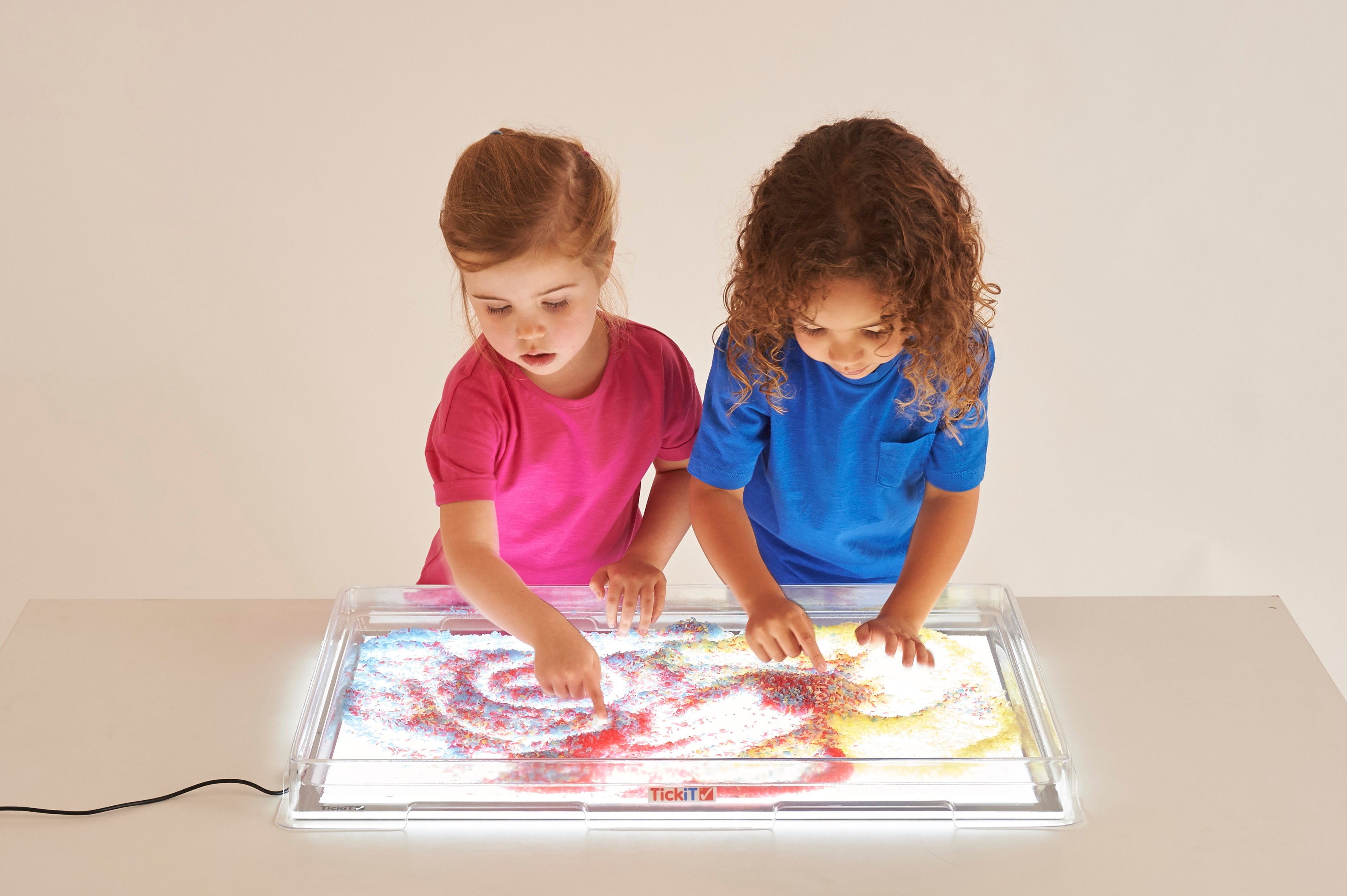 Light panel and cover with two children spreading glow colors across the tray