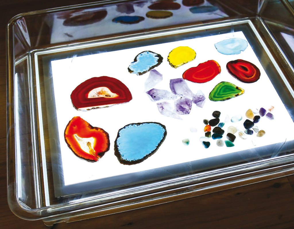 Clear light-up art tray with colorful paint shapes under bright light