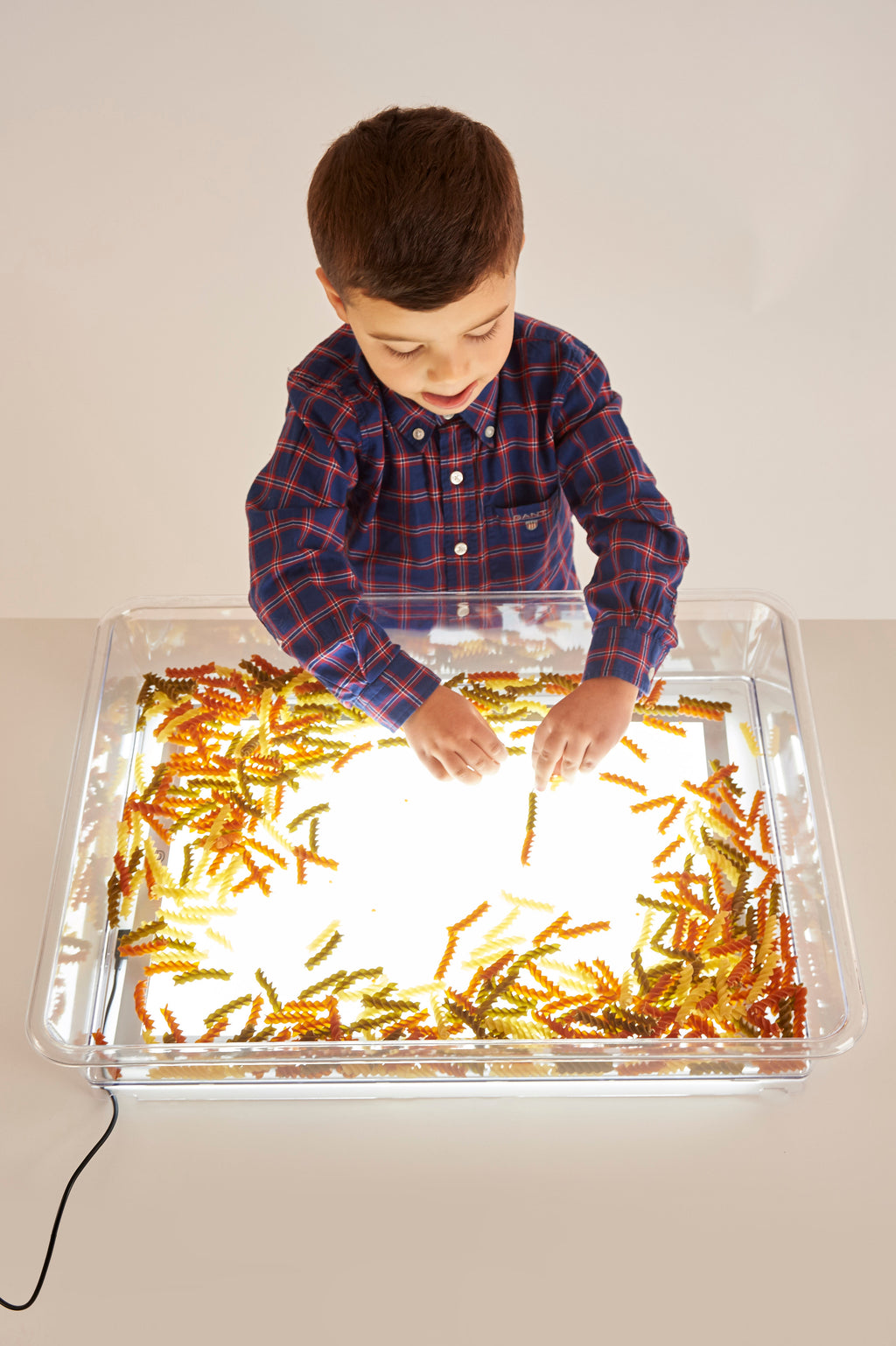 Clear light-up art tray with child hands making golden craft pattern