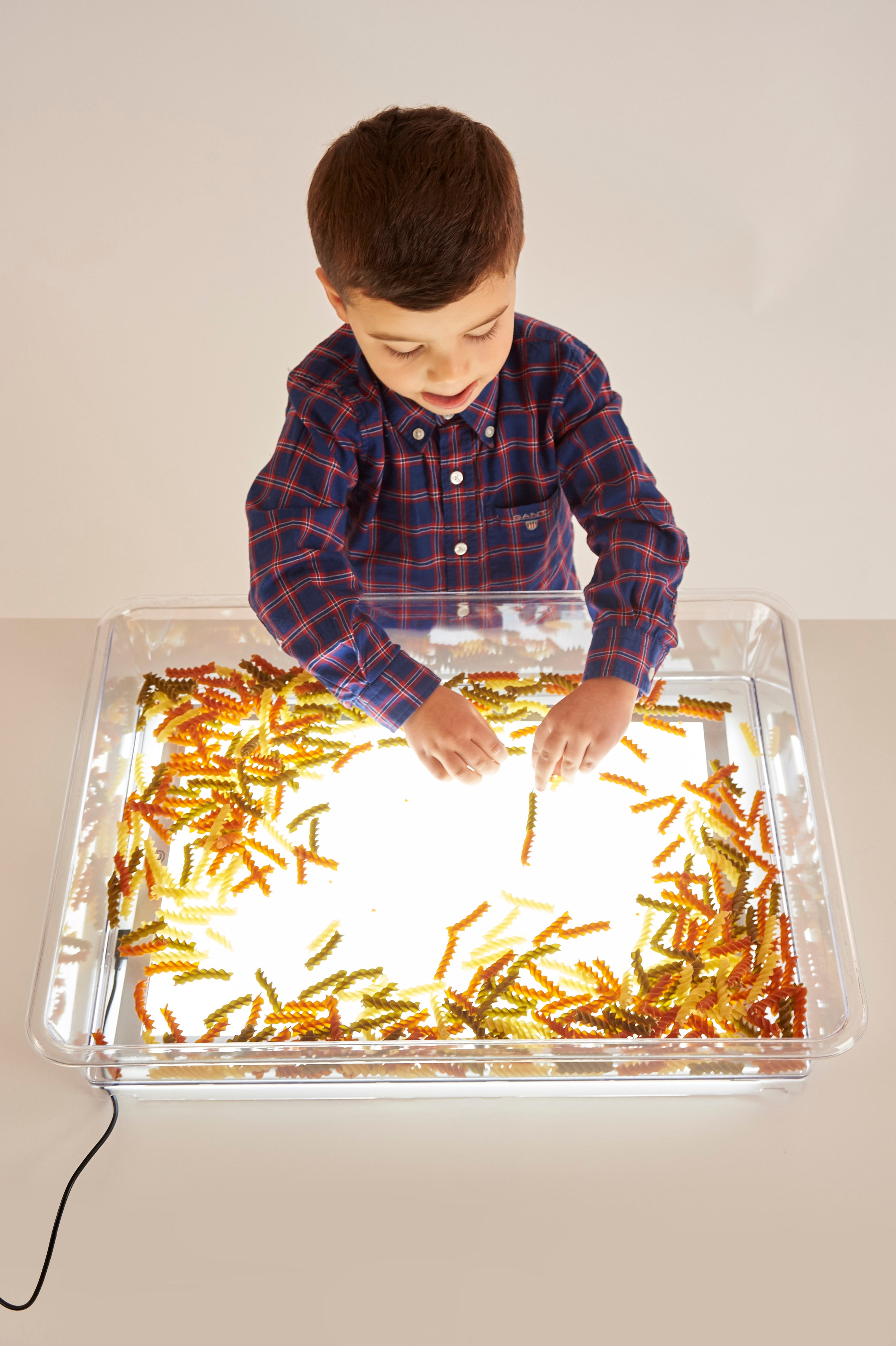 Clear light-up art tray with child hands making golden craft pattern