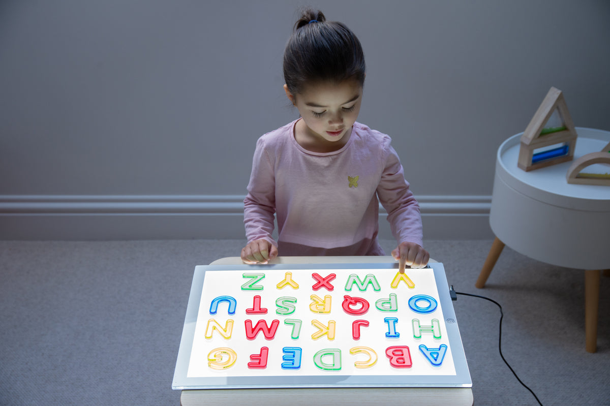 A3 light panel with girl tracing colorful letters on the glowing screen