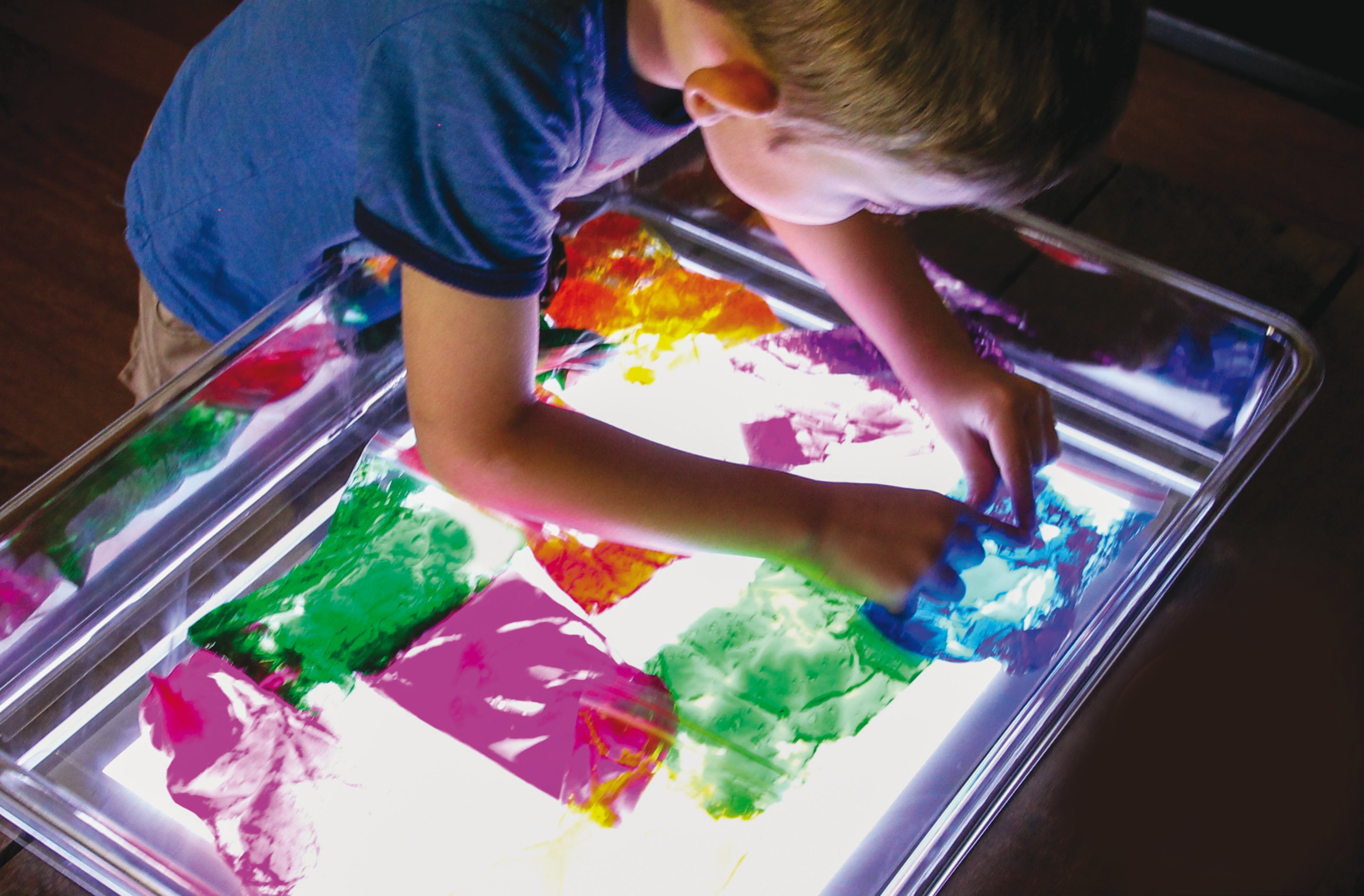 Clear tray over a glowing multicolor light panel with colorful paint-like splashes