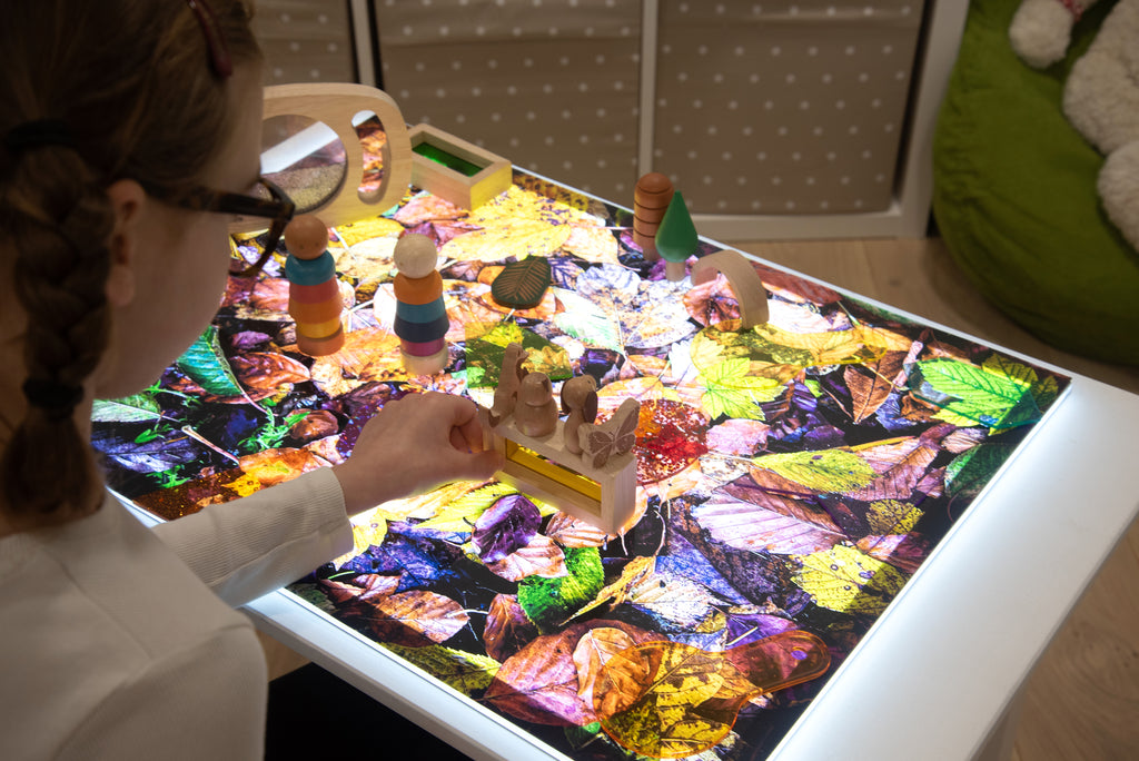 Leaf collage play mat on table with wooden stacking blocks
