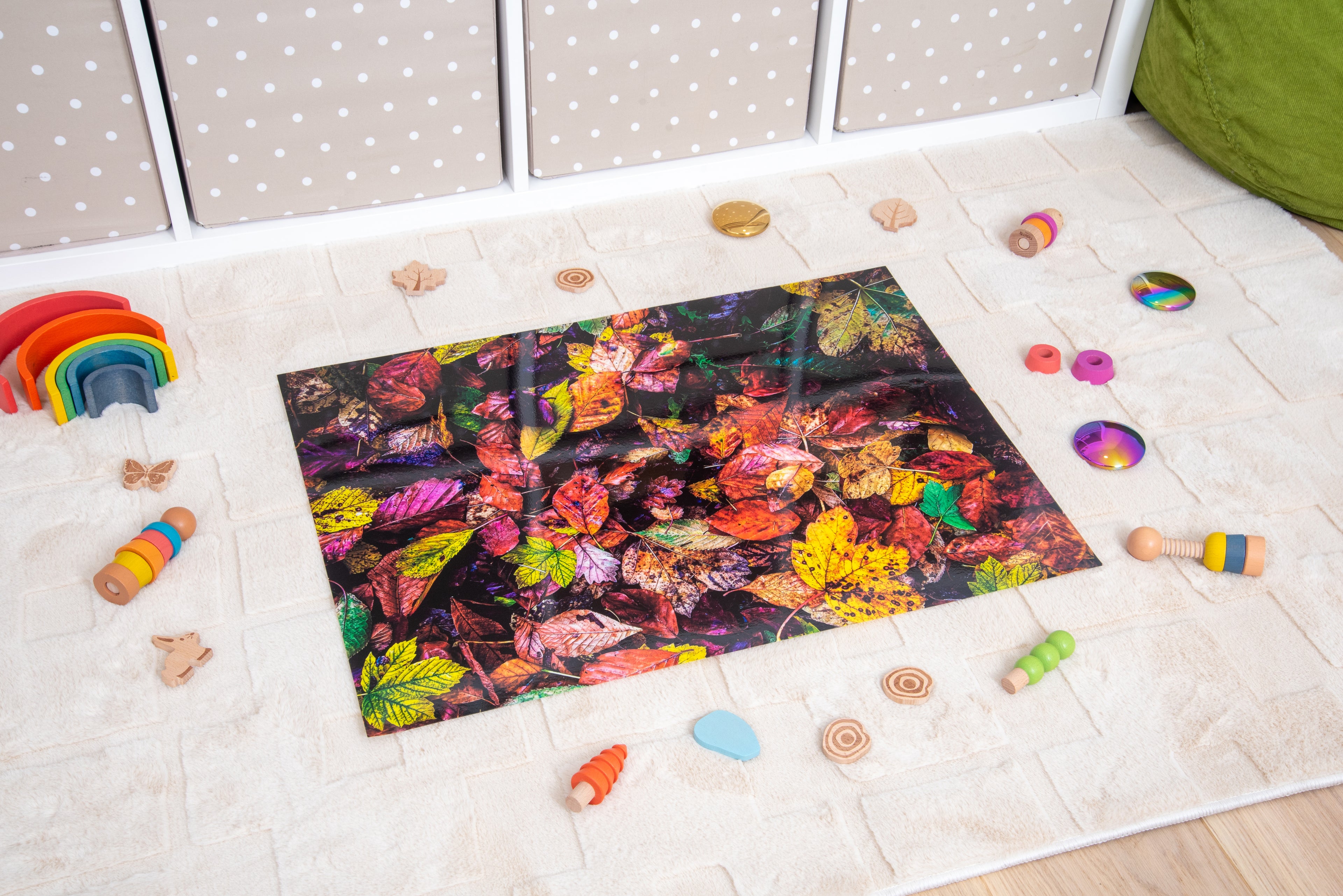Autumn leaf print play mat on floor with colorful plastic toys