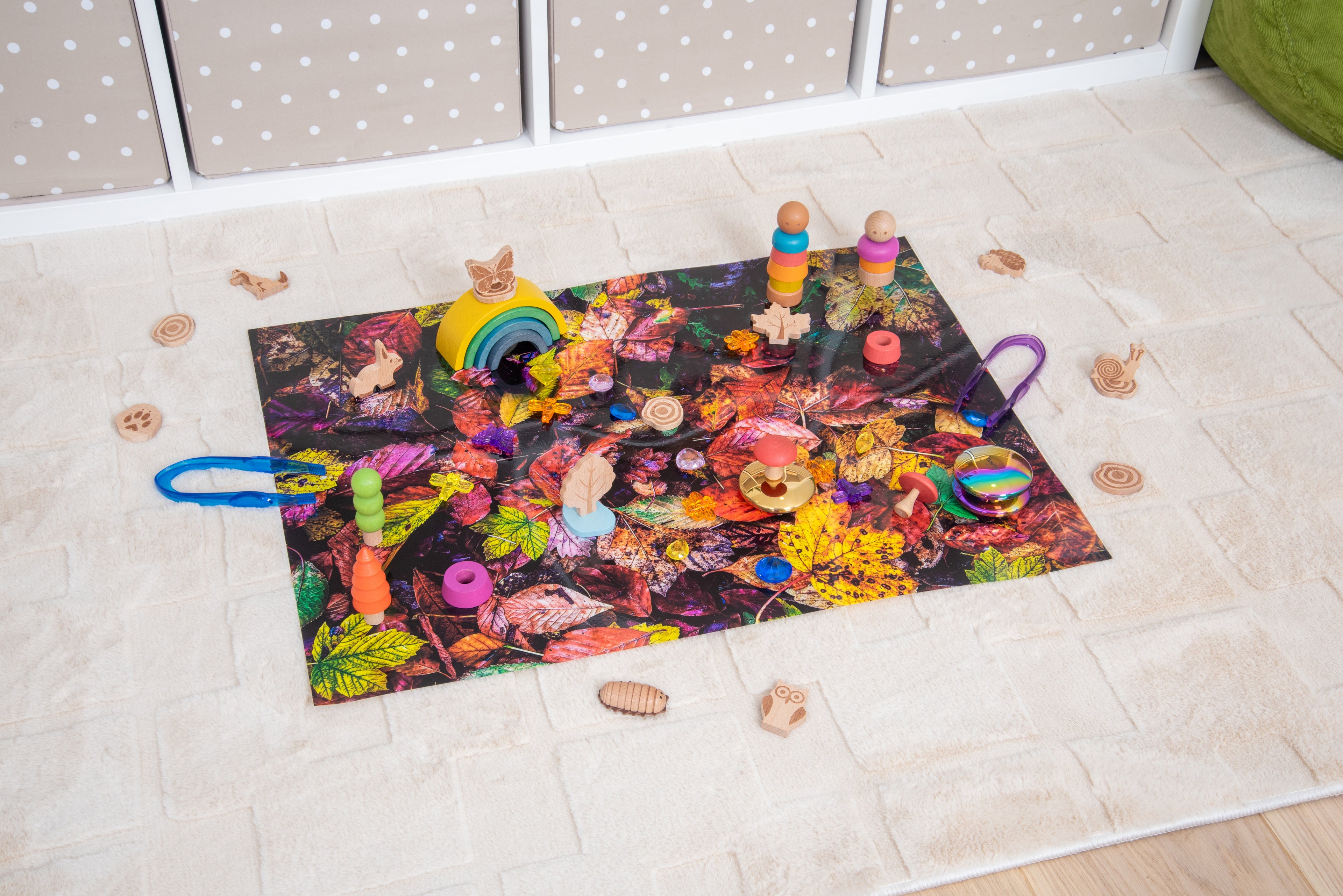 Leaf collage play mat on floor with wooden stacking toys
