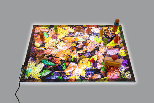 Autumn leaf print play mat with small toy figures near the edges