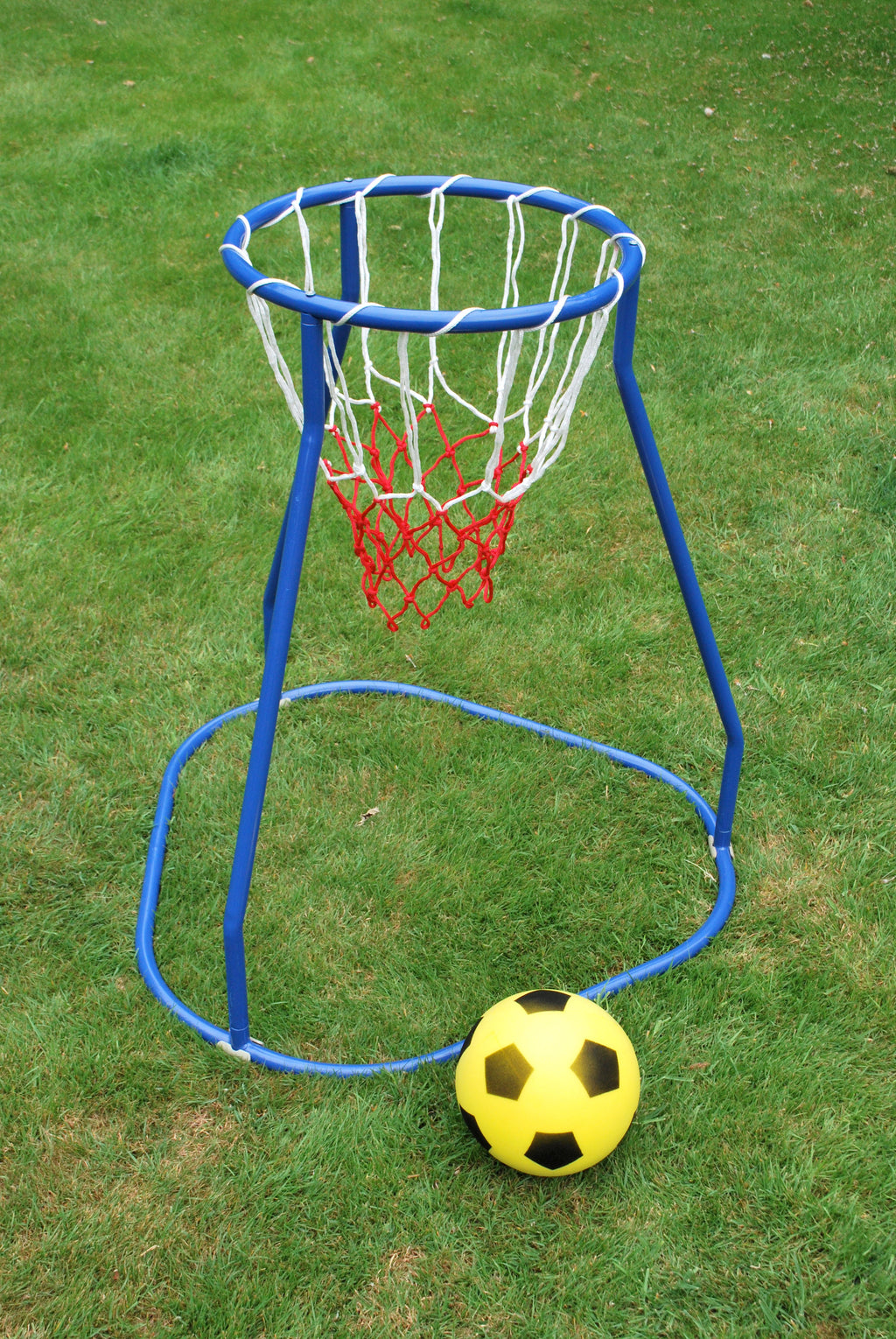 Blue basketball hoop stand with red net on grass, yellow ball near base