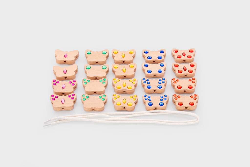 Stacked colorful lacing charms with white cord, grouped by shape