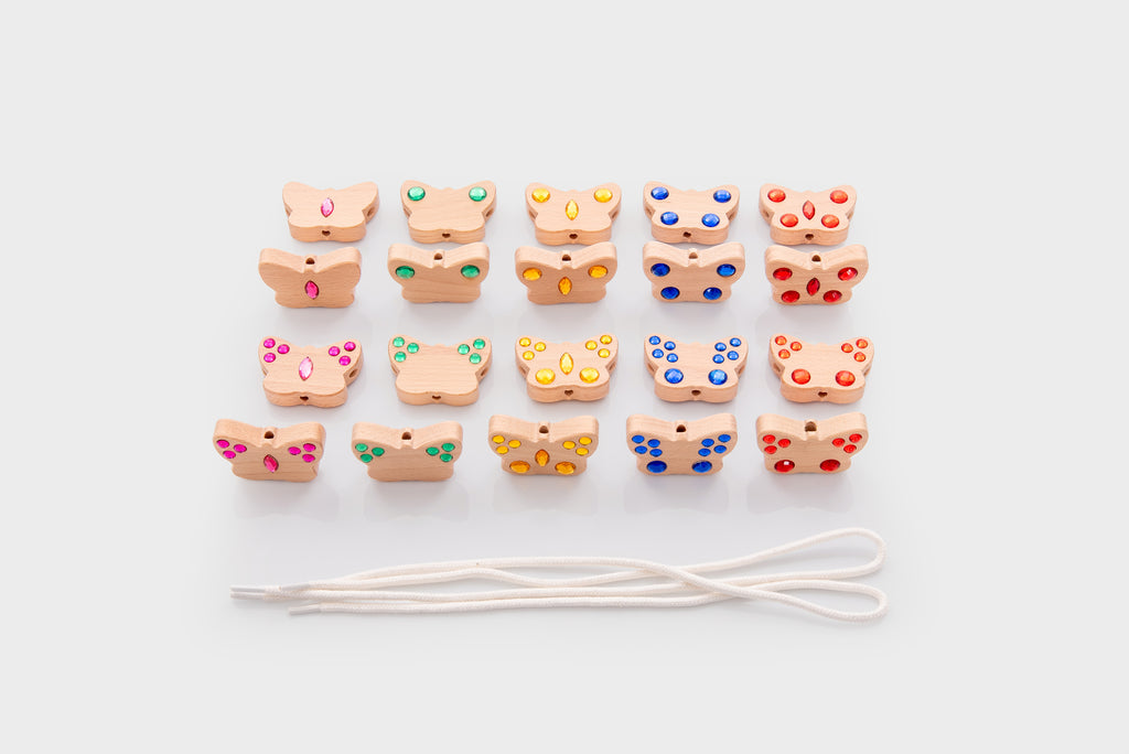 Mixed-color lacing bead charms with white cord, arranged in a loose grid