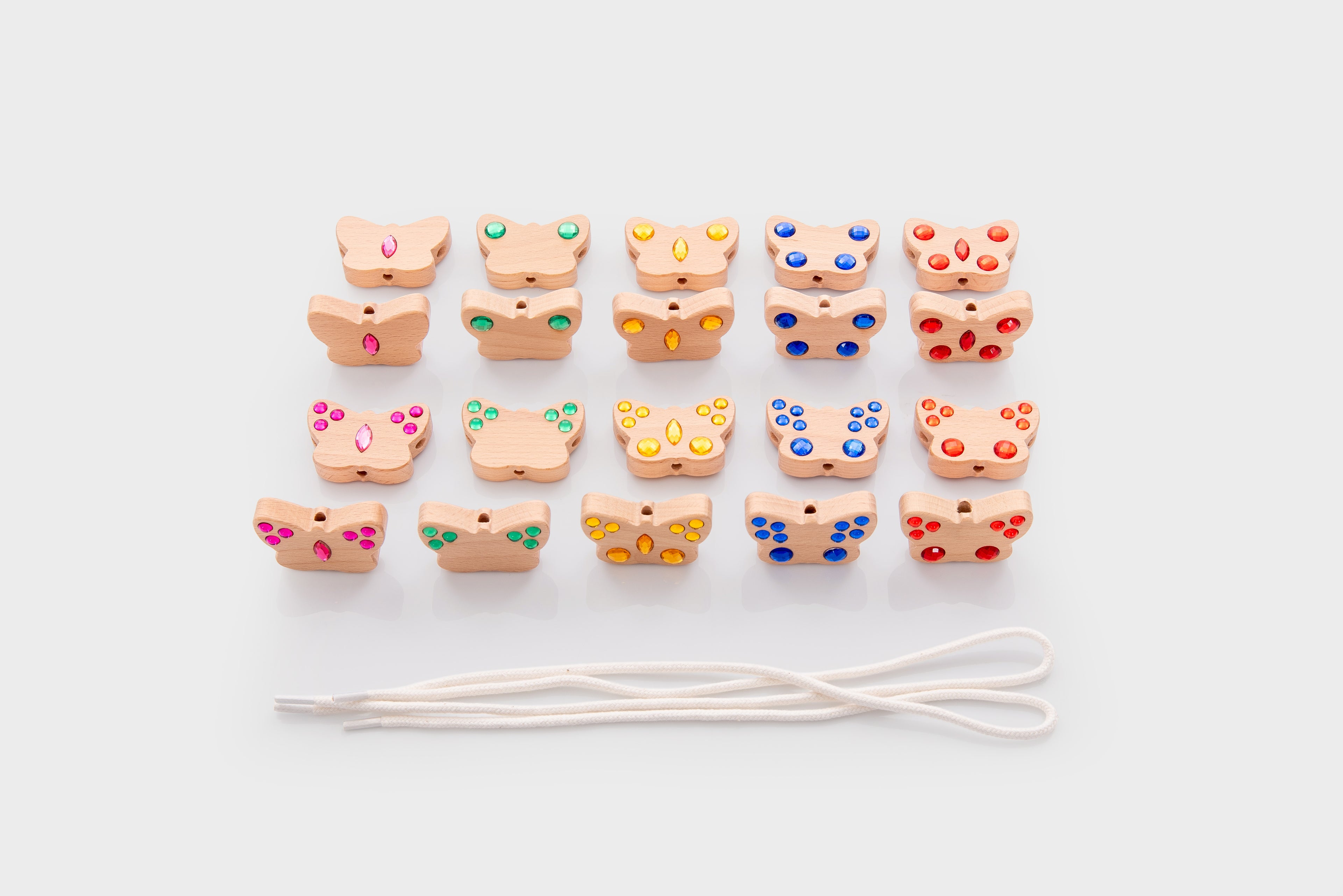 Mixed-color lacing bead charms with white cord, arranged in a loose grid