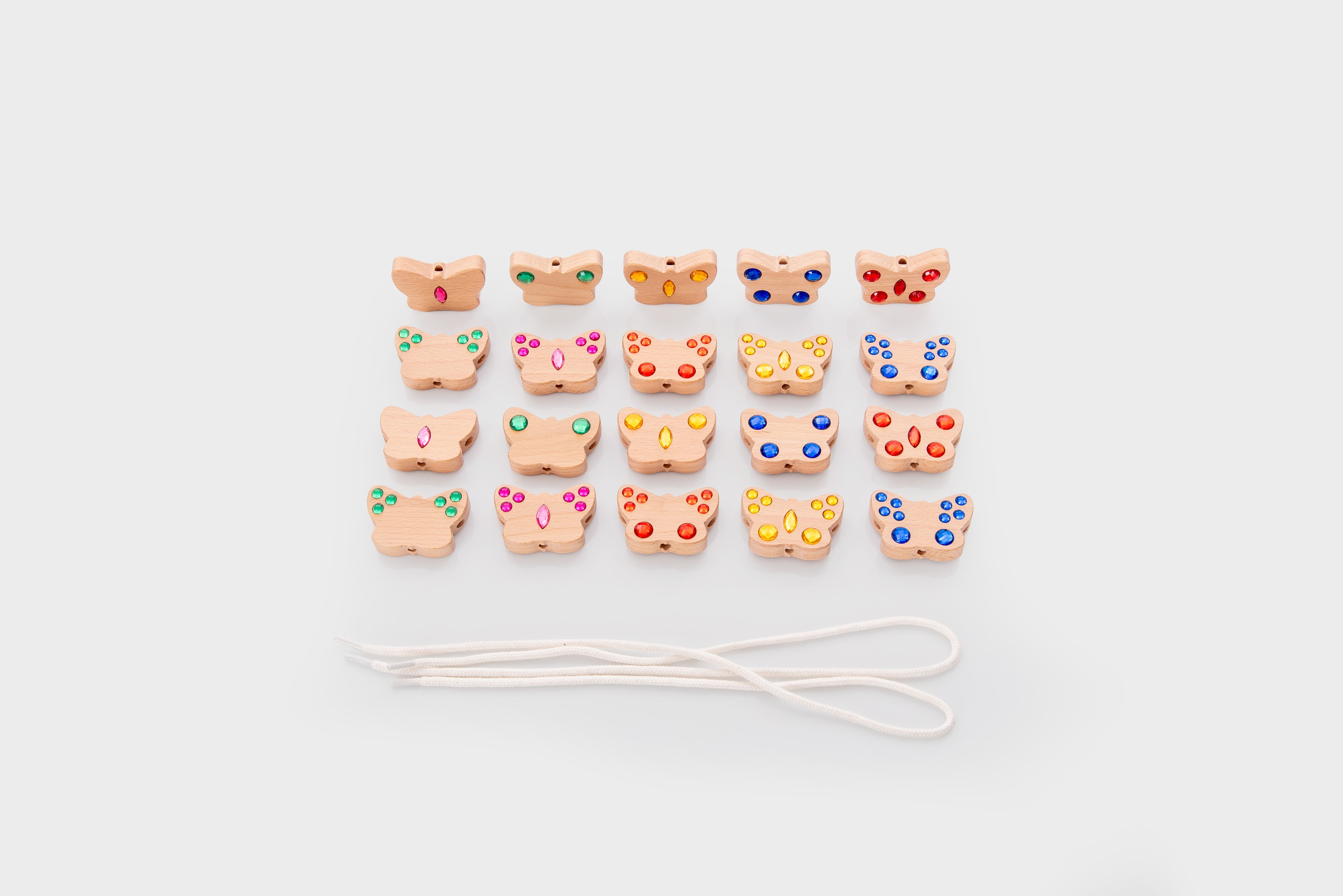 Small shaped lacing charms with white cord on a clean flat surface