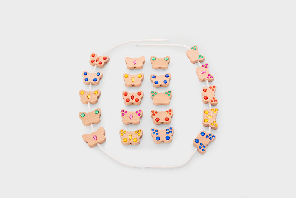 Colorful lacing bead set with shaped charms and white cord, laid out in a circle