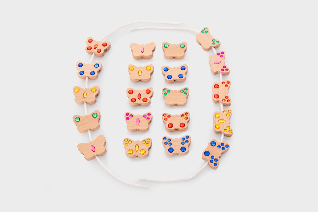 Colorful lacing beads with shaped charms and white cord, laid out flat