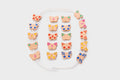 Colorful lacing beads with shaped charms and white cord, laid out flat