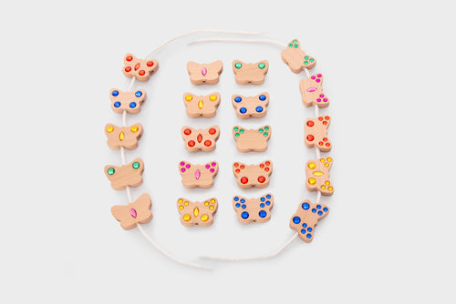 Colorful lacing beads with shaped charms and white cord, laid out flat