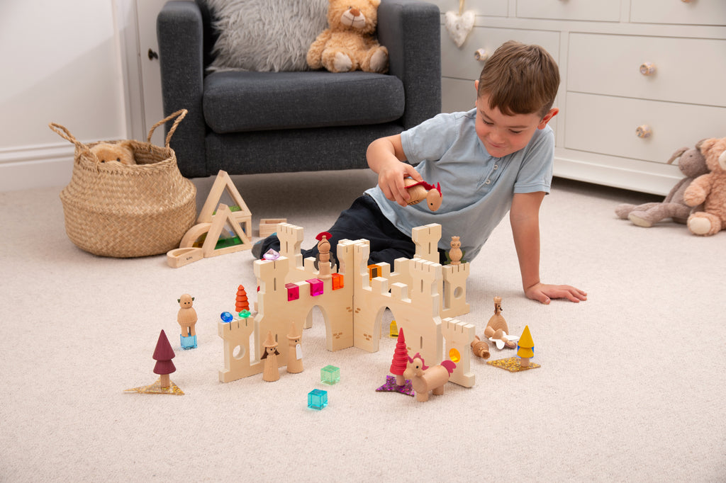 Off-white castle divider set with mini figures, trees, and colorful pieces on the floor