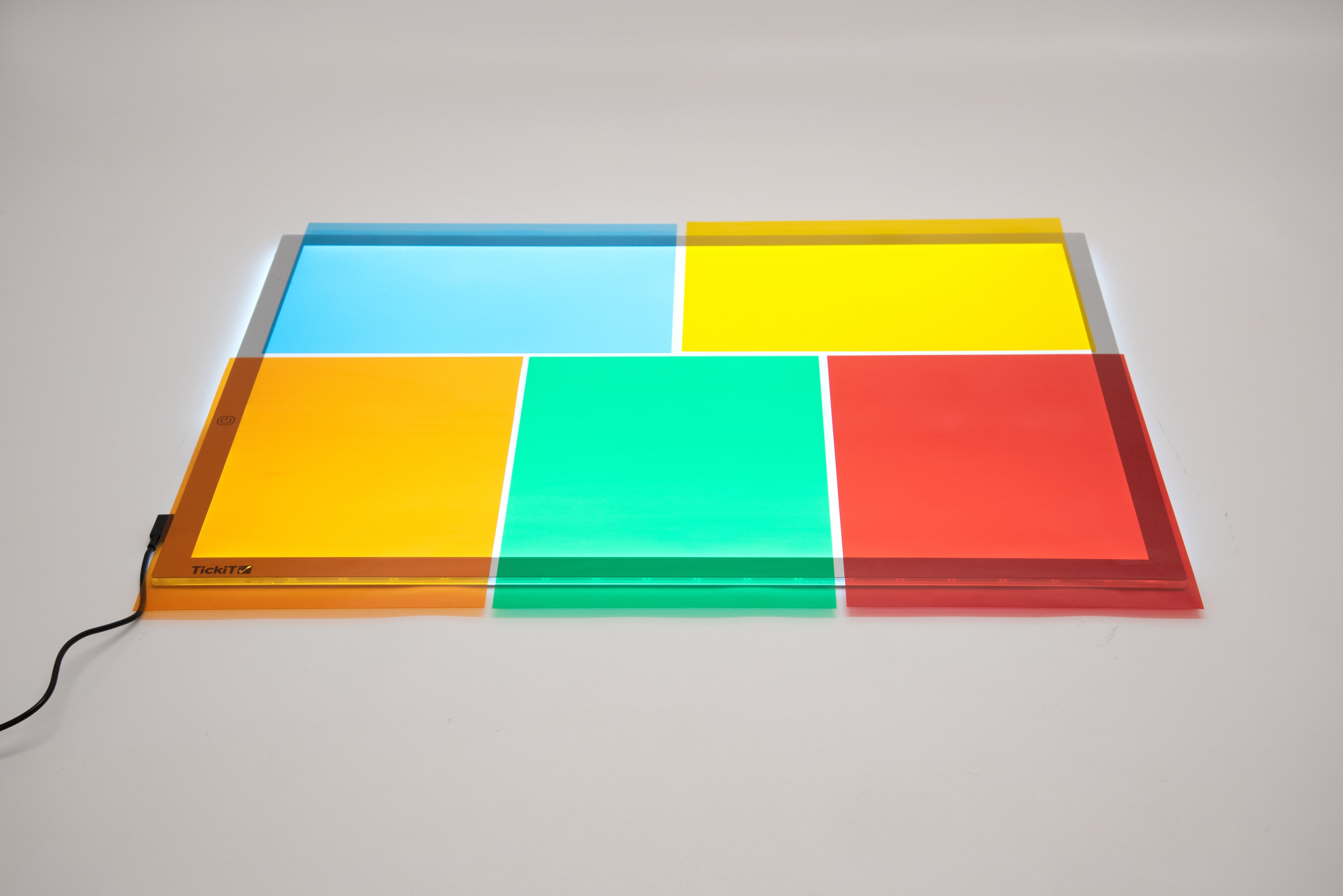 Colored acetate sheets on a flat tray, transparent geometric panels in blue, green, yellow, and red