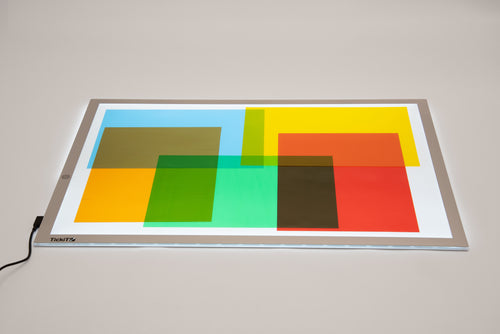 Colored acetate sheets on a lighted tray, geometric transparent panels in bright blocks