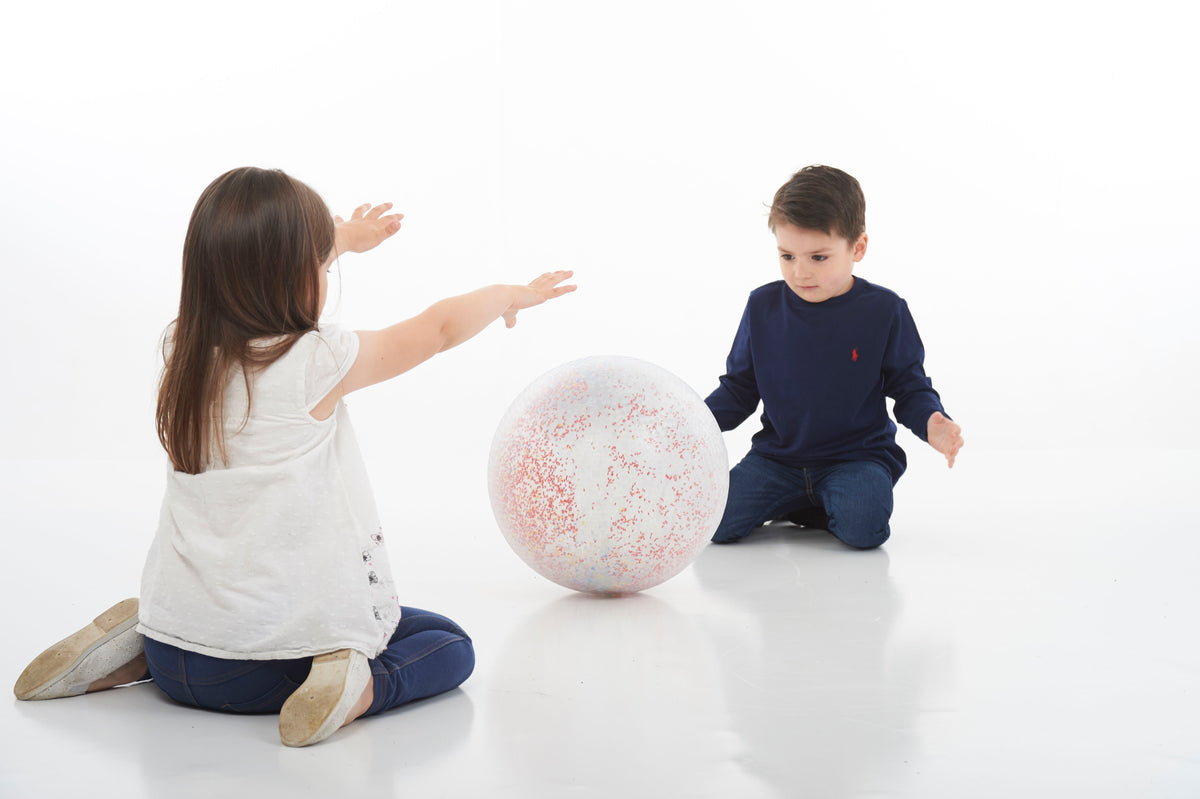 White inflatable confetti-speckled ball being reached by two kids