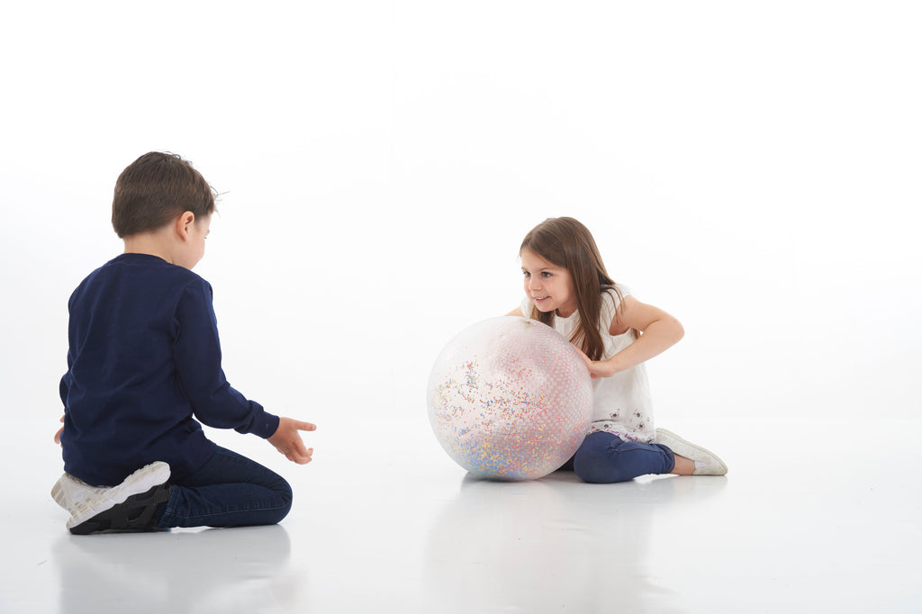 White inflatable confetti-speckled ball between kneeling kids