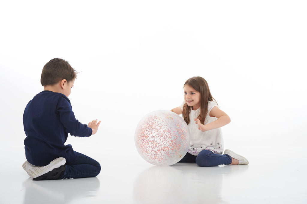 White inflatable confetti-speckled ball between two seated kids
