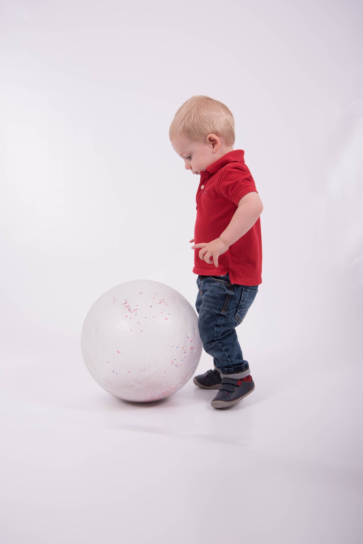 White inflatable confetti-speckled ball with child pushing it forward