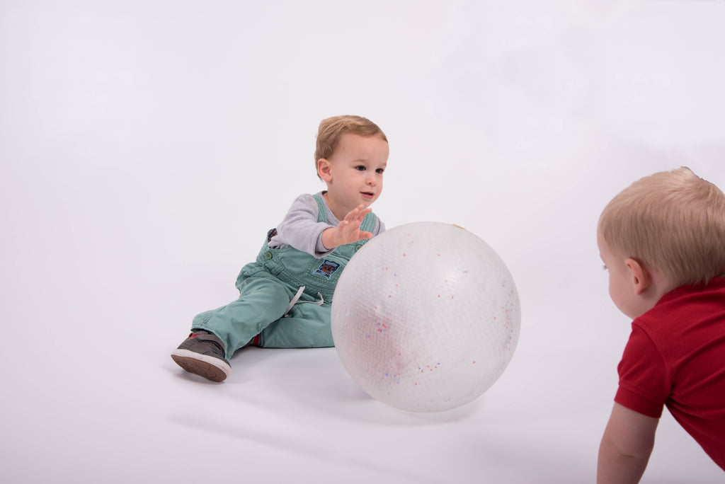 White inflatable confetti-speckled ball with child crawling beside it
