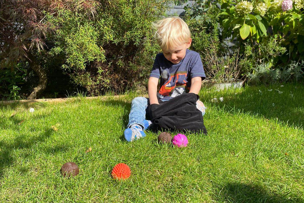 Kids activity ball set on grass: colorful textured balls with black pouch