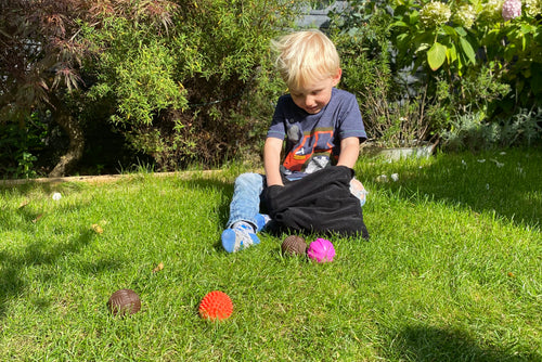 Kids activity ball set on grass: colorful textured balls with black pouch