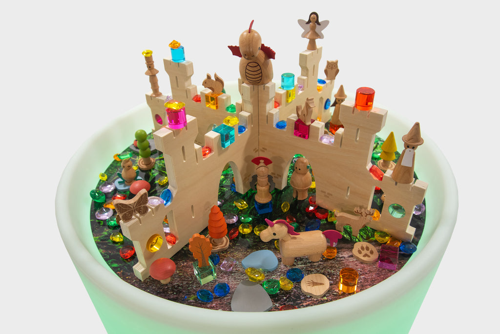 Top view of the illuminated castle play table with colorful figurines and accessories