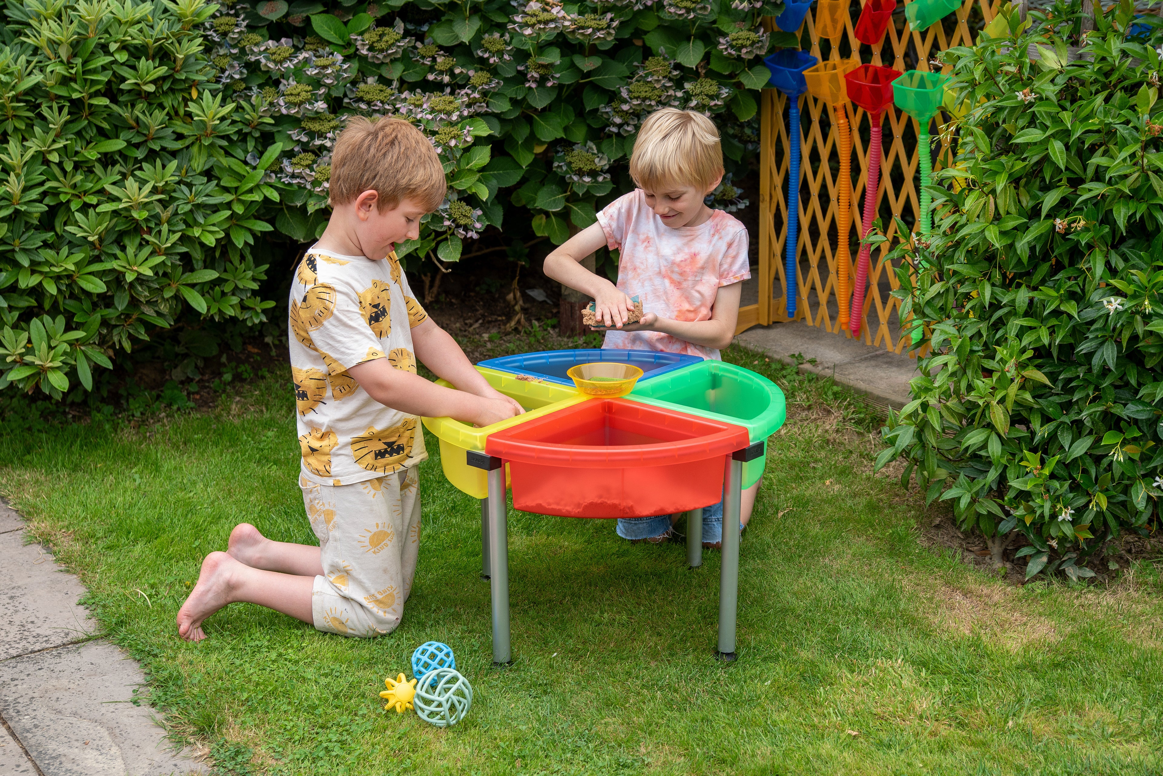 Quadrant color tray set with stand beside garden plants, red and green sand bins