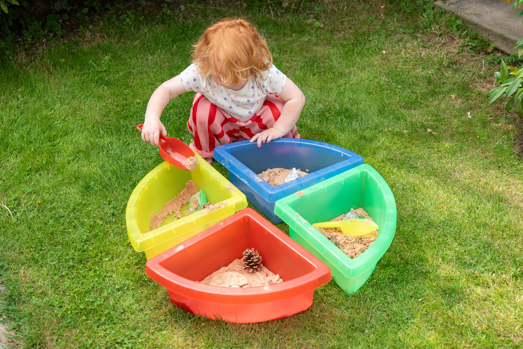 Four-part plastic sand tray set in multicolor as a child plays on grass