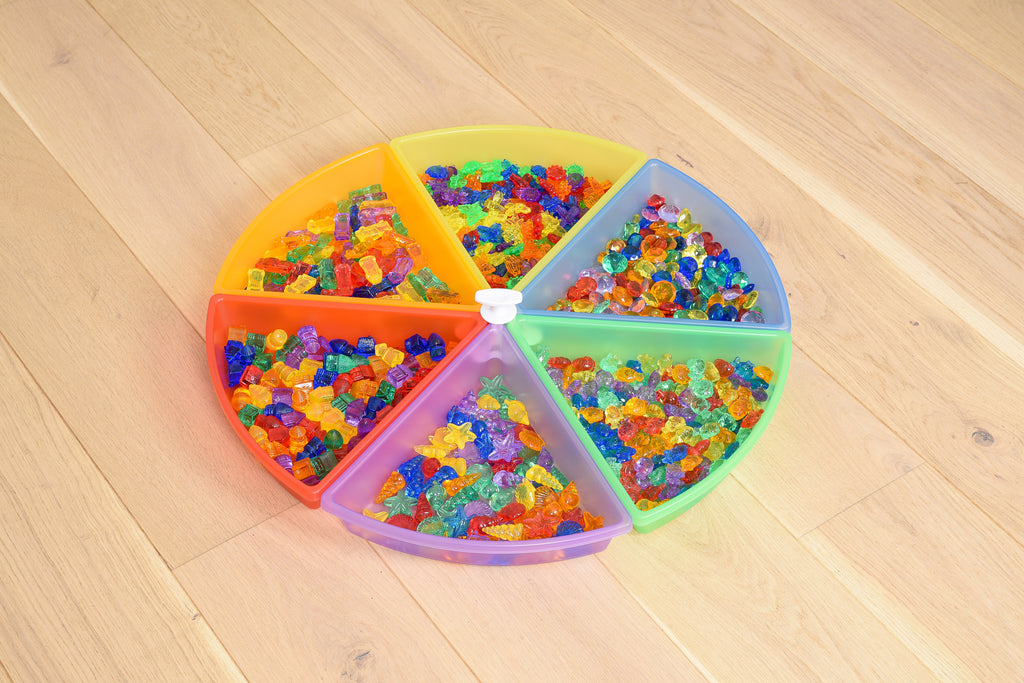 Round plastic color tray set with 6 rainbow compartments on a light wood floor