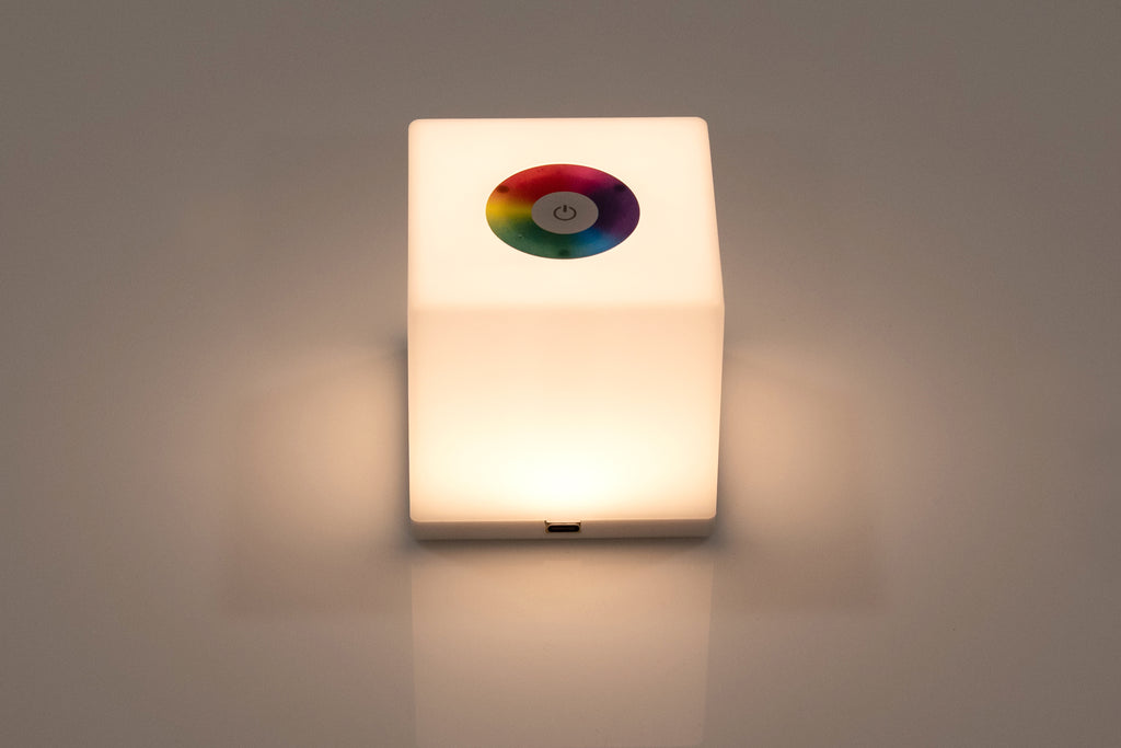 Mini cube LED lamp glowing warm white with circular top lens