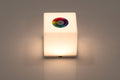 Mini cube LED lamp glowing warm white with circular top lens