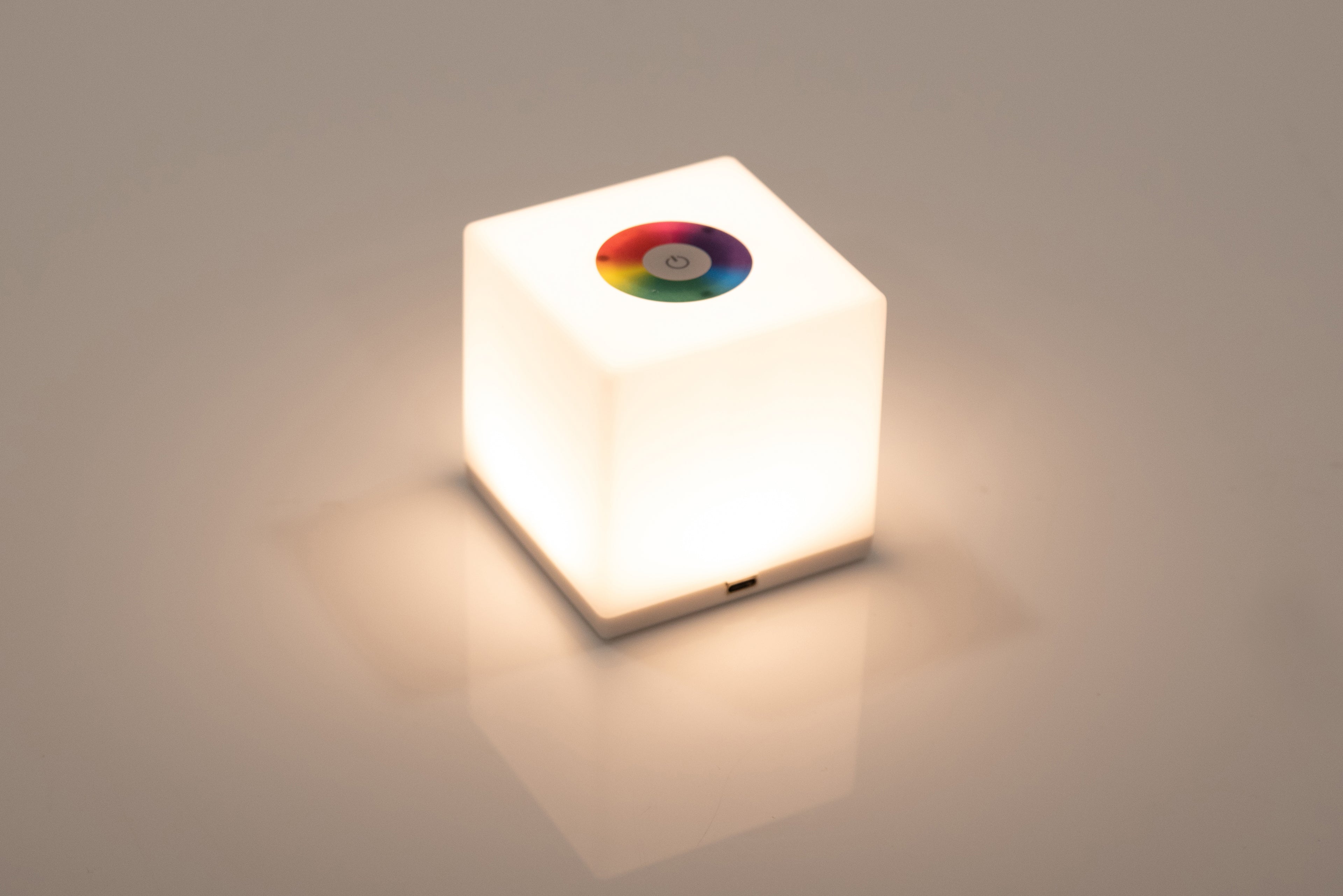 Mini cube LED lamp glowing bright white with circular top lens