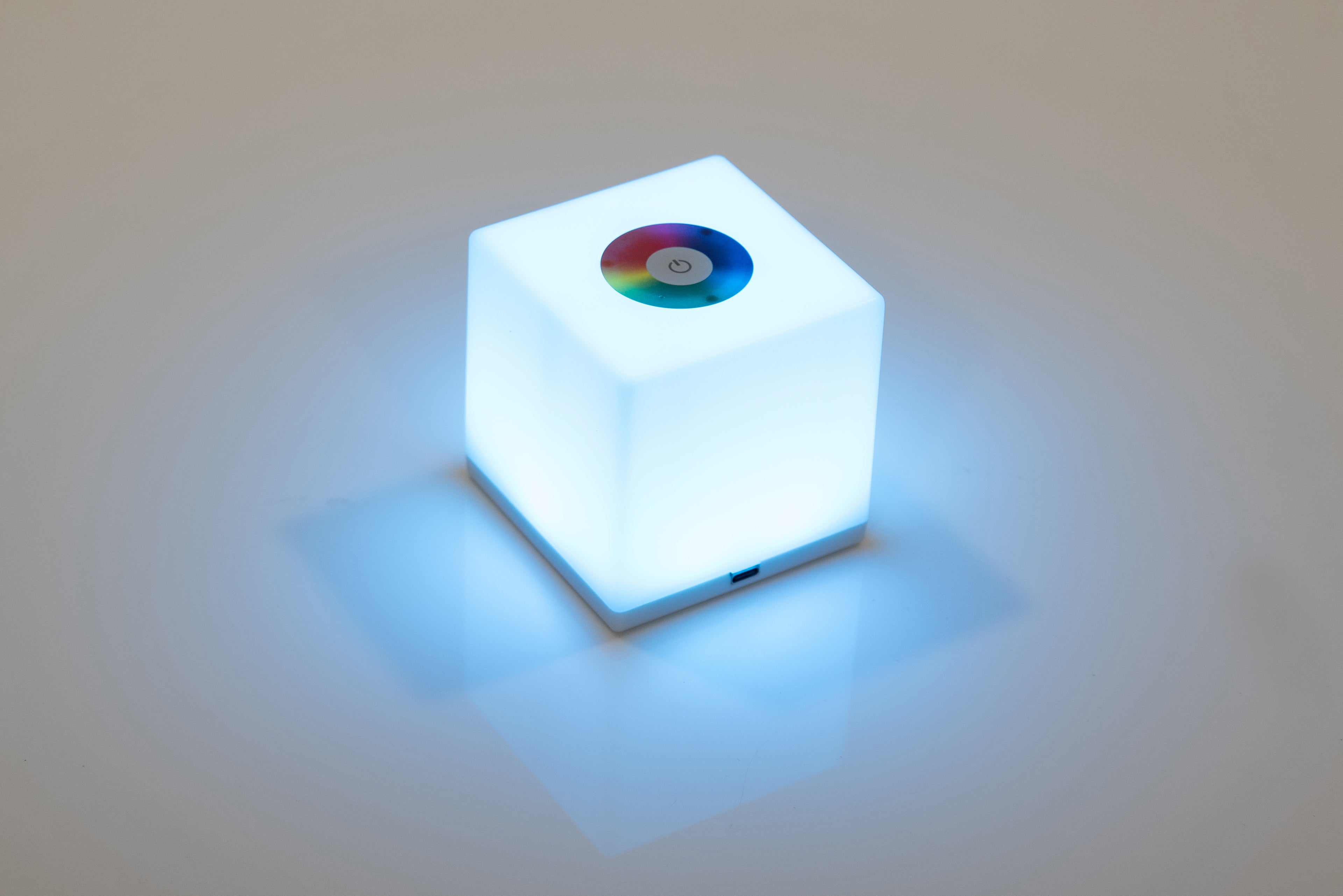 Mini cube LED lamp glowing cool blue with circular top lens